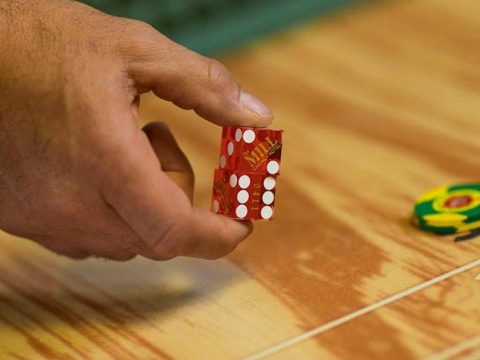 Hand rolling dice at a table game of craps.