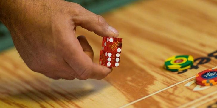 Hand rolling dice at a table game of craps.
